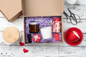 Seasonal gift box for valentine day with candle, red cup and heart shape sweets