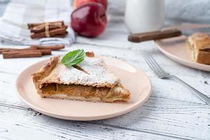 Homemade piece of apple pie with fresh red apples on white table photo