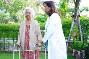 Asian elderly woman disability patient walk with walker in park, medical concept. photo