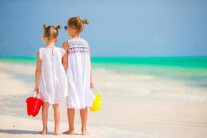 Little adorable girls with beach toys at tropical beach photo