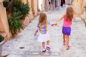 Adorable happy little girls outdoors in narrow street at small city photo