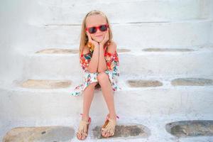 niña en las escaleras en calles antiguas y mykonos. niño en la calle del típico pueblo tradicional griego con paredes blancas y puertas coloridas en la isla de mykonos, en grecia foto