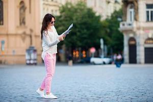 Happy young woman with a city map in city. Travel tourist woman with map in Prague outdoors during holidays in Europe. photo