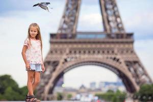 adorable niña en el fondo de parís la torre eiffel durante las vacaciones de verano foto