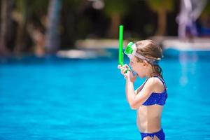 Adorable little girls at mask and goggles in pool photo