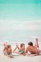 padre e hijos pequeños disfrutando de vacaciones tropicales de verano en la playa foto