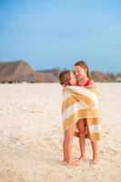 Little girls wrapped in towel after swimming at tropical beach photo