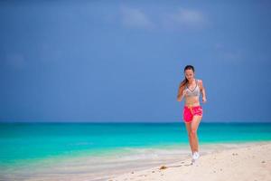 Colocar joven corriendo a lo largo de la playa tropical en su ropa deportiva foto