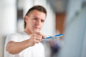 Young man with small airplane in airport waiting his flight photo