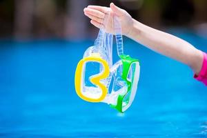 Two wet scuba masks in kid hand near swimming pool photo