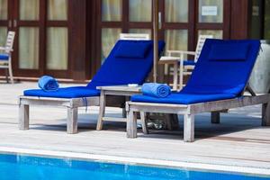 Blue towels on loungers near swimming pool at tropical resort photo