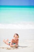 Adorable little girl at white beach during summer vacation photo