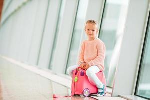 Adorable little girl in airport with her luggage waiting for boarding photo