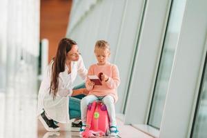 Happy family at airport sitting on suitcase with boarding pass waiting for boarding photo