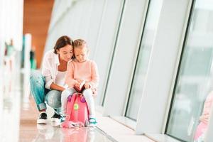 Happy family at airport sitting on suitcase with boarding pass waiting for boarding photo