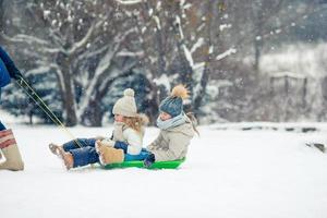 Adorable little happy girls sledding in winter snowy day. photo