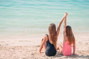 Little happy funny girls have a lot of fun at tropical beach playing together. photo