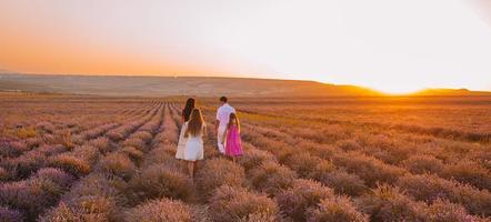 Family in lavender flowers field at sunset in white dress and hat photo