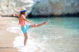 Adorable active little girl at beach during summer vacation photo