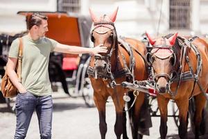 Tourist man enjoying a stroll through Vienna and looking at the two horses in the carriage photo