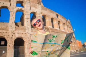 adorable niña activa con mapa frente al coliseo en roma, italia. niño pasando la infancia en europa foto