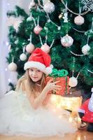 Little cute girl near christmas tree. Children under Christmas tree with gift boxes. photo