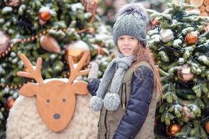 Little happy girl near fir-tree branch in snow for new year. photo