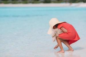 adorable niña con sombrero en la playa durante las vacaciones de verano foto