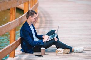 Young man with laptop working outdoors in the park photo