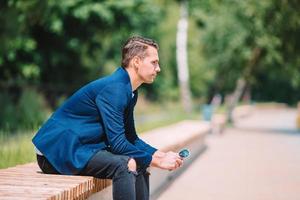 Man is reading text message on mobile phone while walking in the park photo