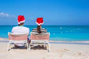 Happy couple wearing Santa hat at caribbean beach photo