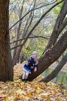 Little girl in autumn park on fall day outdoors photo