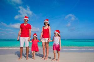 Happy family in Christmas Hats on white beach photo