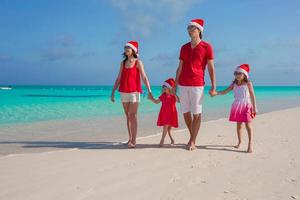 Happy family of four in Christmas Hats during tropical vacation photo