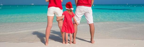 familia feliz de tres en sombreros de navidad durante vacaciones tropicales foto