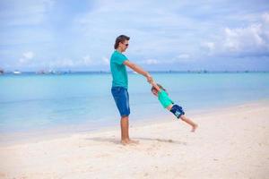 Young dad and his little daughter on tropical white sand beach photo