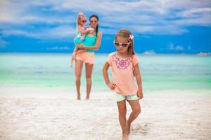 Beautiful mother and her little daughters at exotic beach photo