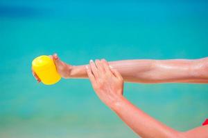 Manos femeninas con fondo de botella de crema solar mar azul foto