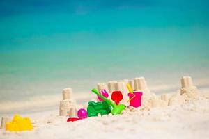 castillo de arena en la playa blanca con juguetes de plástico para niños foto