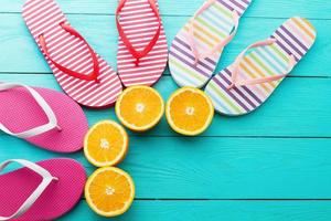 Summer fun time and flip flops. Slippers and orange fruit on blue wooden background. Mock up and picturesque. Top view. Copy space photo