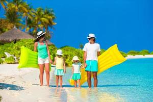 Happy family of four on white beach photo