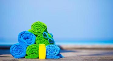 Beach and summer vacation accessories concept - close-up of colorful towels, swimming goggles and sunblock photo
