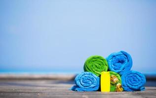 Beach and summer vacation accessories concept - close-up of colorful towels, swimming goggles and sunblock photo