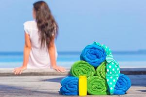 concepto de accesorios de playa y verano: toallas coloridas, traje de baño y fondo solar hermosa mujer foto