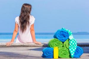 concepto de accesorios de playa y verano: toallas coloridas, traje de baño y fondo solar hermosa mujer foto