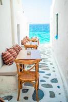 bancos con almohadas en un típico café griego al aire libre en mykonos con impresionantes vistas al mar en las islas cícladas foto