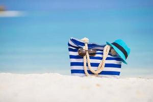 accesorios de playa - bolso azul, sombrero de paja, gafas de sol en la playa blanca foto