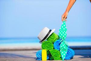 Beach and summer vacation accessories concept - close-up of colorful towels, hat, bag and sunblock photo