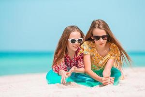 Two little happy girls have a lot of fun at tropical beach playing together photo