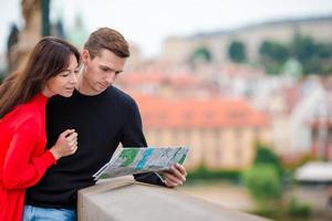 Young tourist couple traveling on holidays in Europe smiling happy. Caucasian family with city map in search of attractions photo